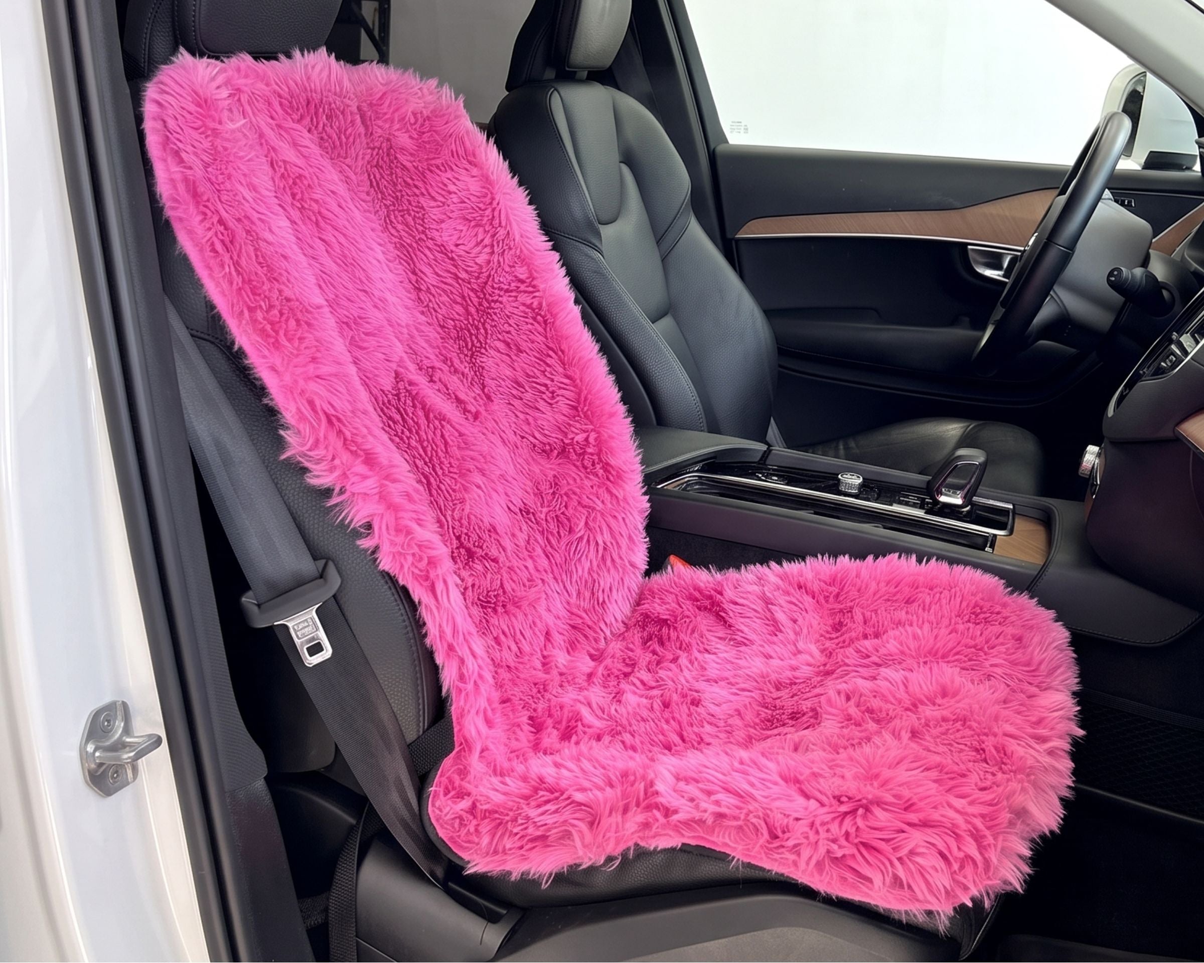 Bowsers Single Seat Cover A bright pink faux fur car seat cover installed on a black leather car seat, shown inside a vehicle cabin.