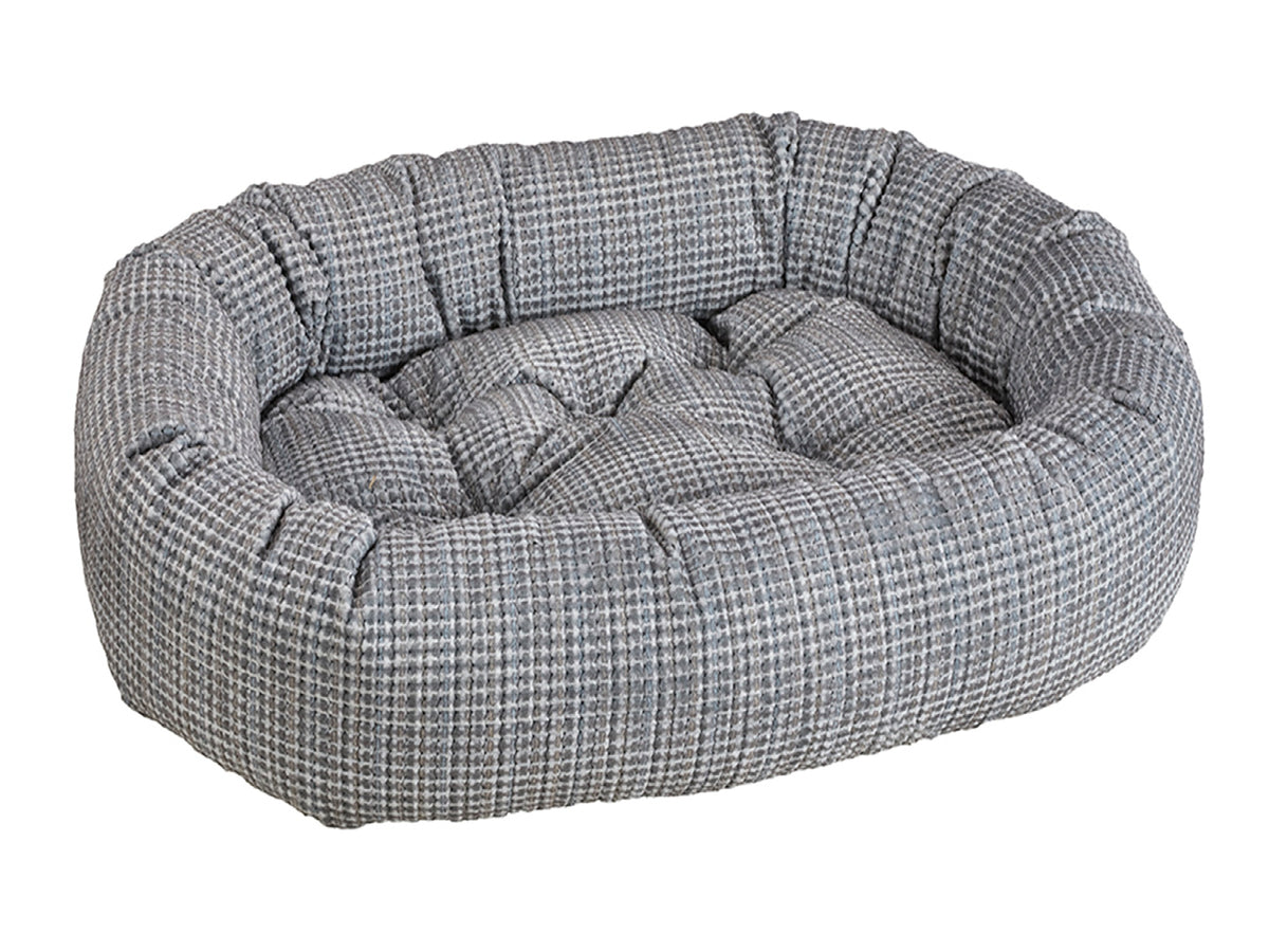 A round, tufted pet bed with a gray and white houndstooth patterned fabric, shown on a solid white background.