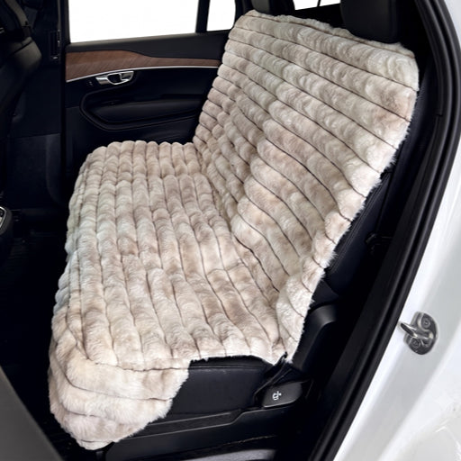 Bowsers Bench Seat Cover A plush faux fur car seat cover in a light beige and cream color, shown installed on a car's rear seat inside a vehicle.