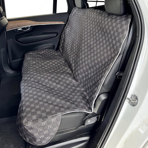 Bowsers Bench Seat Cover Signature Noir A car seat cover with a gray and white repeating monogram pattern, shown installed on a vehicle's rear seat.