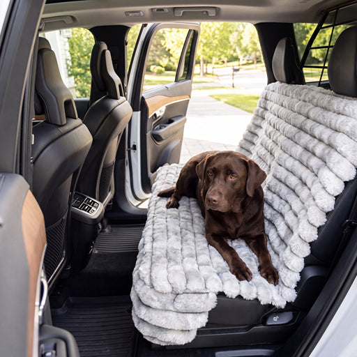 Bowsers Bench Seat Cover Silver Fox A brown dog lies on a plush, cream-colored car seat cover installed in the back of a vehicle. The seat cover has a textured, shaggy surface and is shown in use inside a car with the door open.