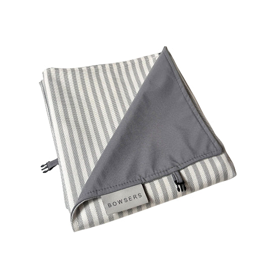 A folded dog travel blanket with a gray and white striped pattern on one side and a solid gray reverse side, featuring a 'BOWSERS' brand tag and a small black 
