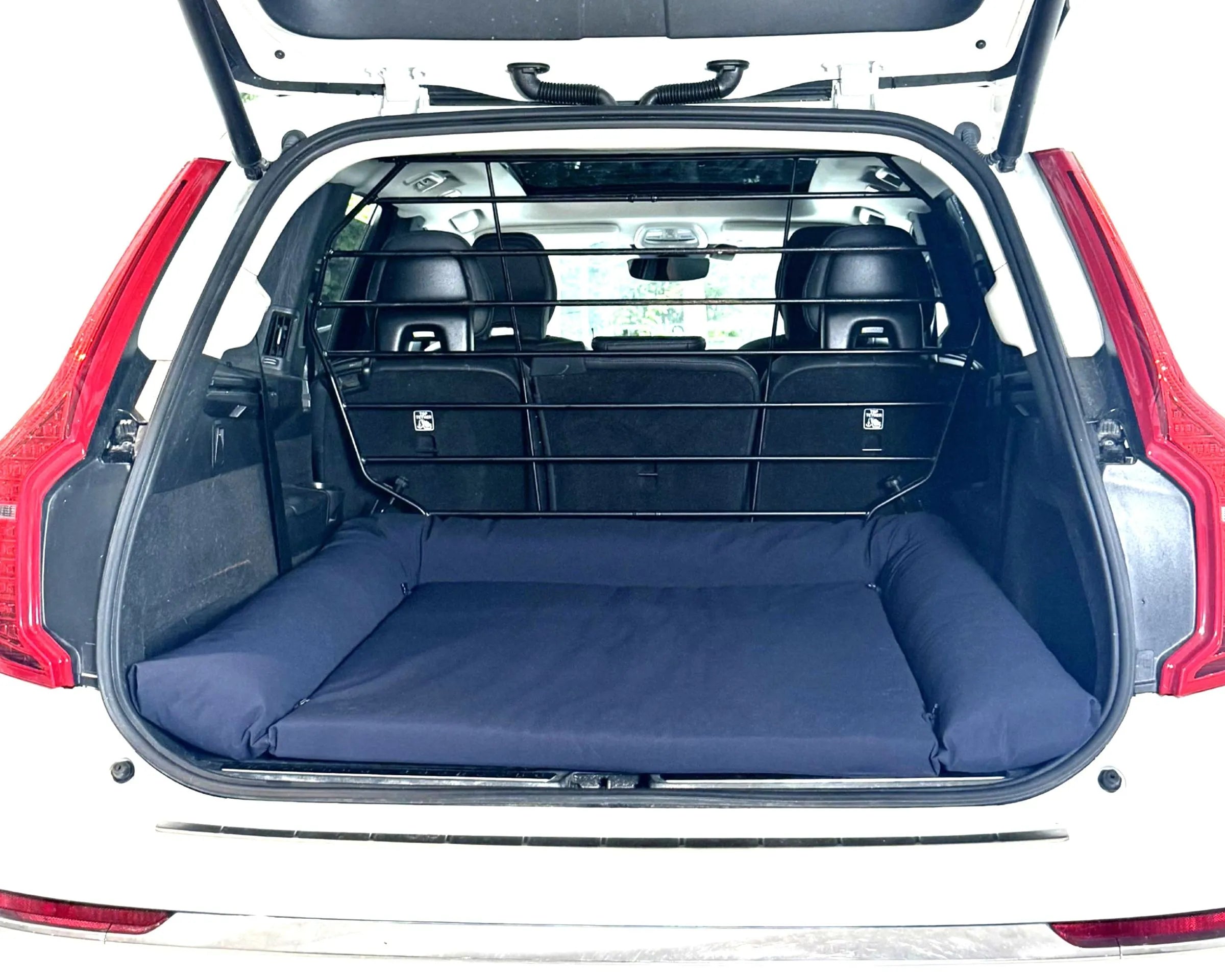 Bowsers SUV Cargo Lounger Dog Bed A navy blue cargo bed mat installed in the open trunk of a white SUV, with the rear seats folded down and a black cargo divider visible in the background.
