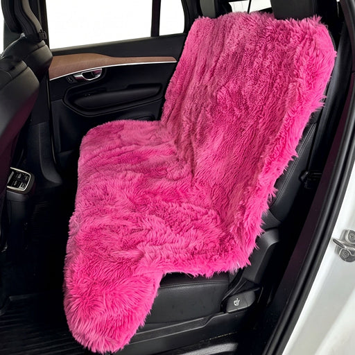 A bright hot pink faux fur car seat cover draped over a black car seat inside a vehicle.