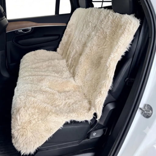 Fluffernutter Bowsers Bench Seat Cover A cream-colored faux fur car seat cover draped over a black car seat, shown inside an open car door.