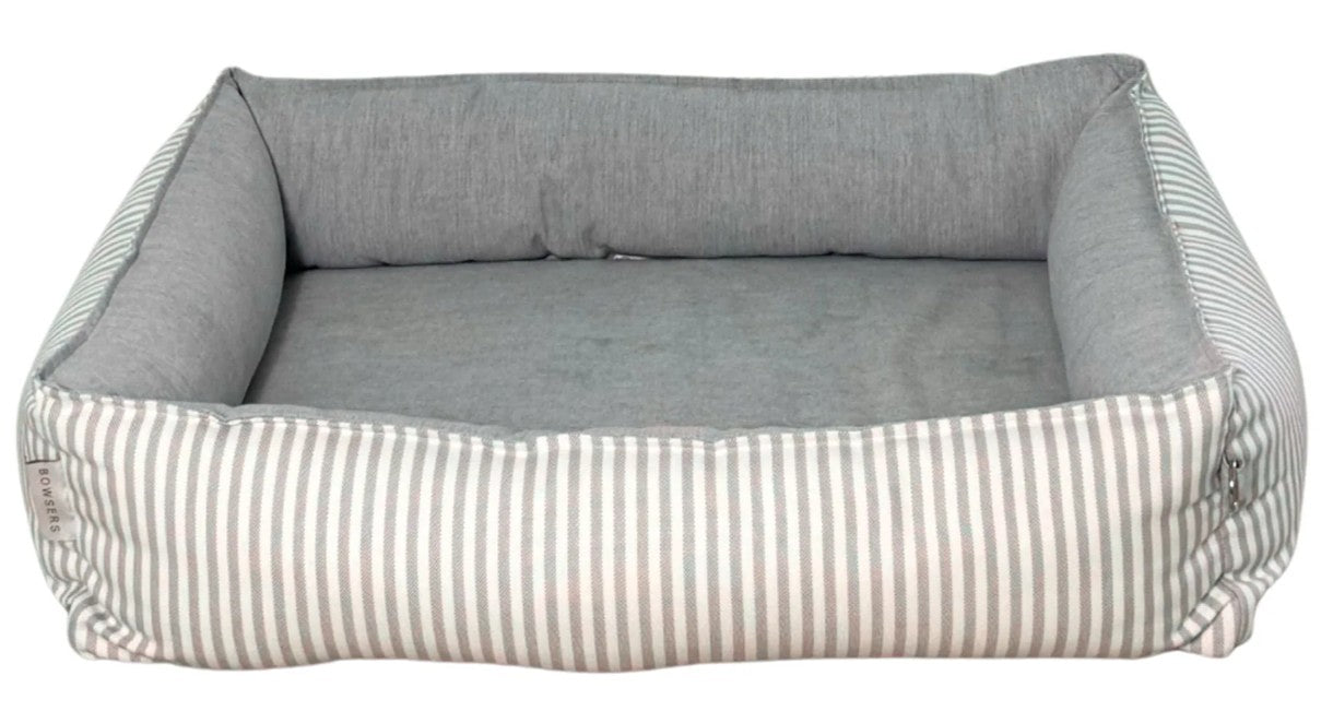 A rectangular pet bed with a high bolstered wall, featuring a solid gray fabric interior and a side and front panel with thin vertical stripes in beige and gray.