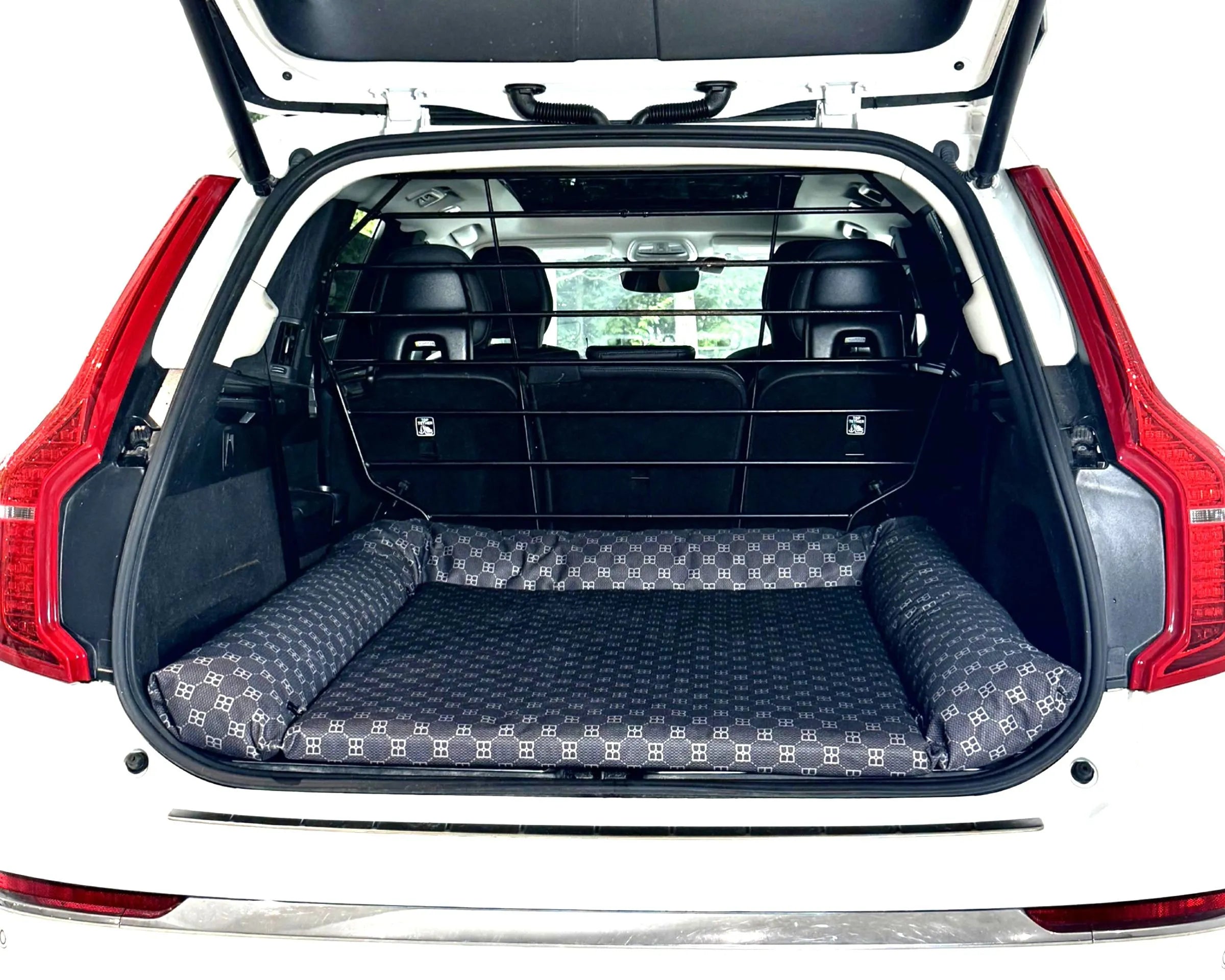 Bowsers SUV Cargo Lounger Dog Bed A black and gray patterned pet car bed installed in the open trunk of a white vehicle, with the rear seats folded down and a black cargo crate behind it.